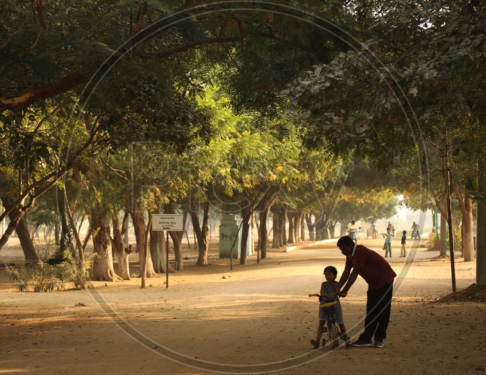 A father helping his daughter with the cycle in the play ground