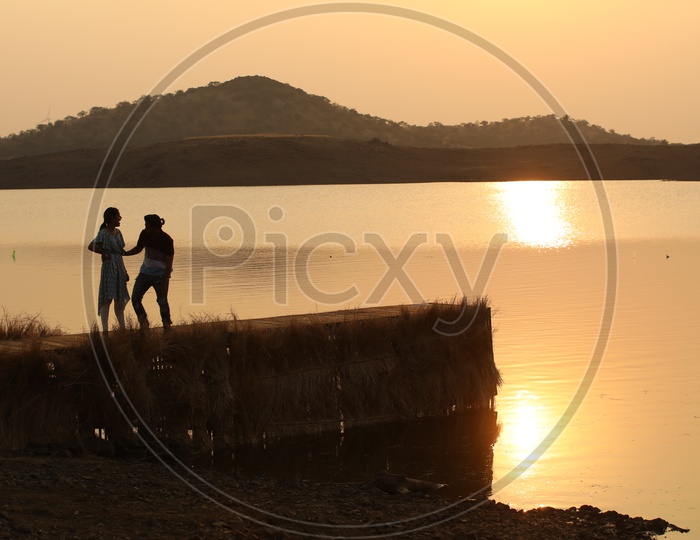 Silhouette Of a Couple on a Wooden Water Bridge At a Lake