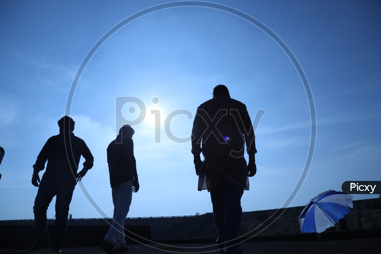Silhouette of three men walking along the bridge side