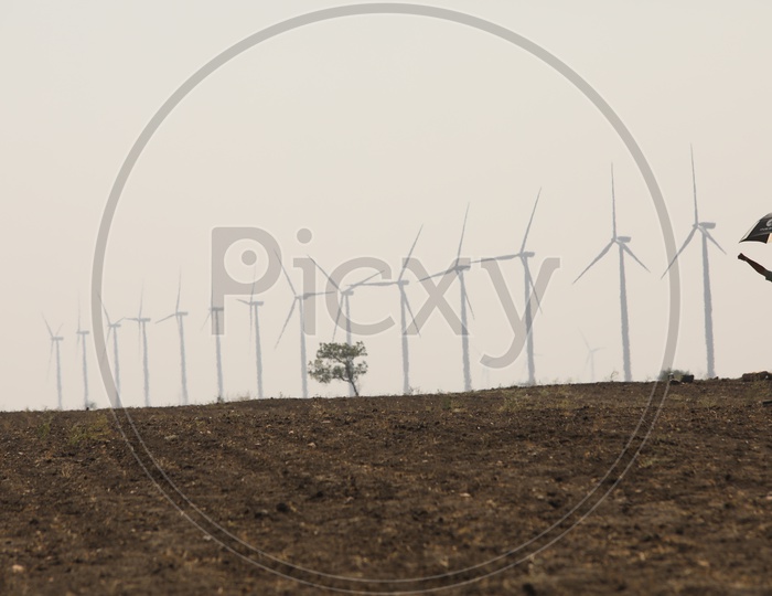 A Man On Barren Lands With Wind Mills In Background