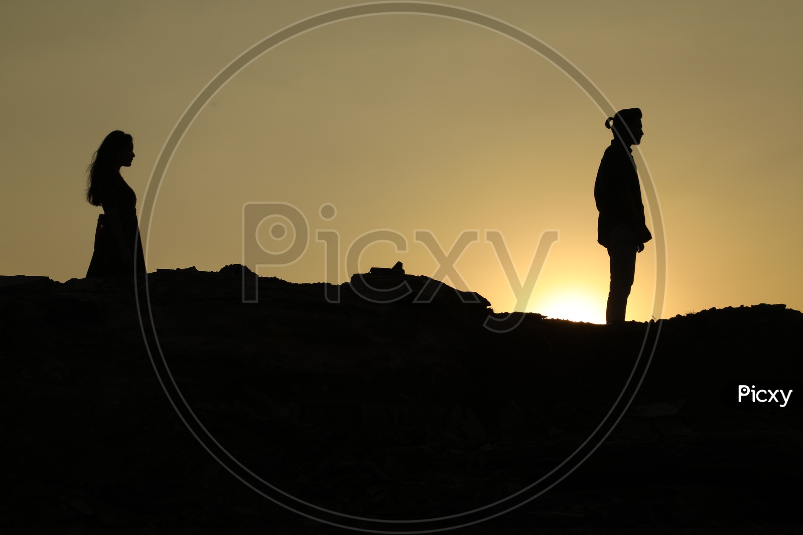 Silhouette of man and woman on the top of the rocky hill