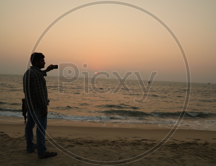 A Man Shooting The Sunset Over Sea