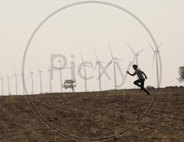 A Man on Barren Land with Wind Mills in Background