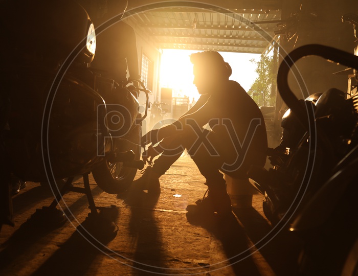 Silhouette Of Bike and Mechanic In Shed