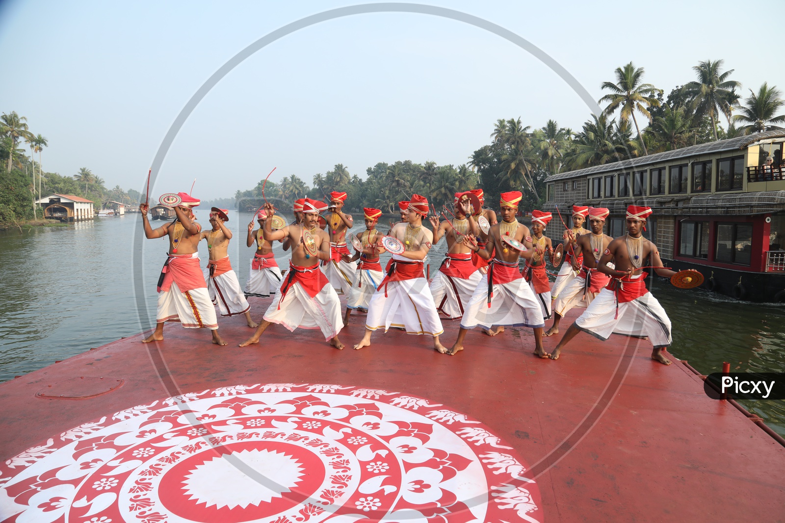 A Group Of Dancers In Kerala Traditional Dancers Attire Dancing On a Boat With Kerala Backwaters Background