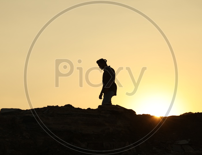 Silhouette of man with a ponytail on the top of the rocky hill