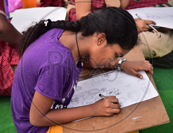 A school girl drawing a sketch during a competition
