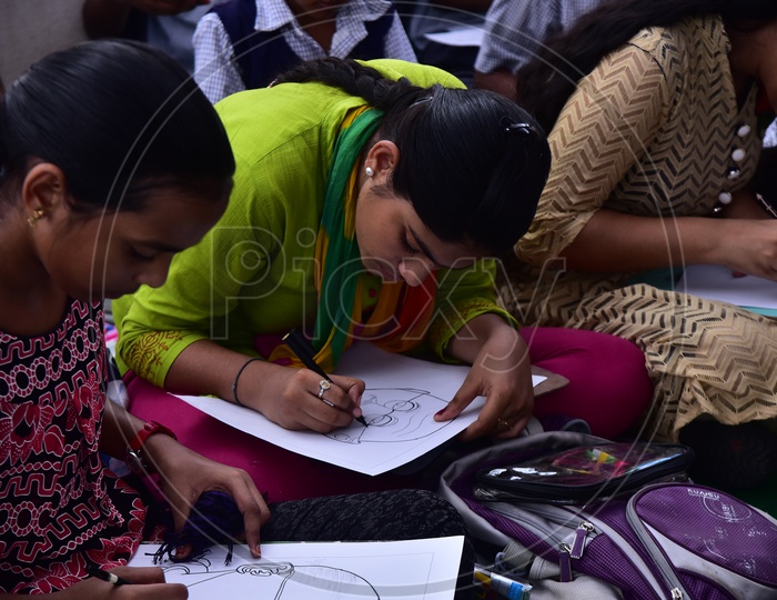 A school girl drawing a sketch of Mahatma Gandhi during a competition