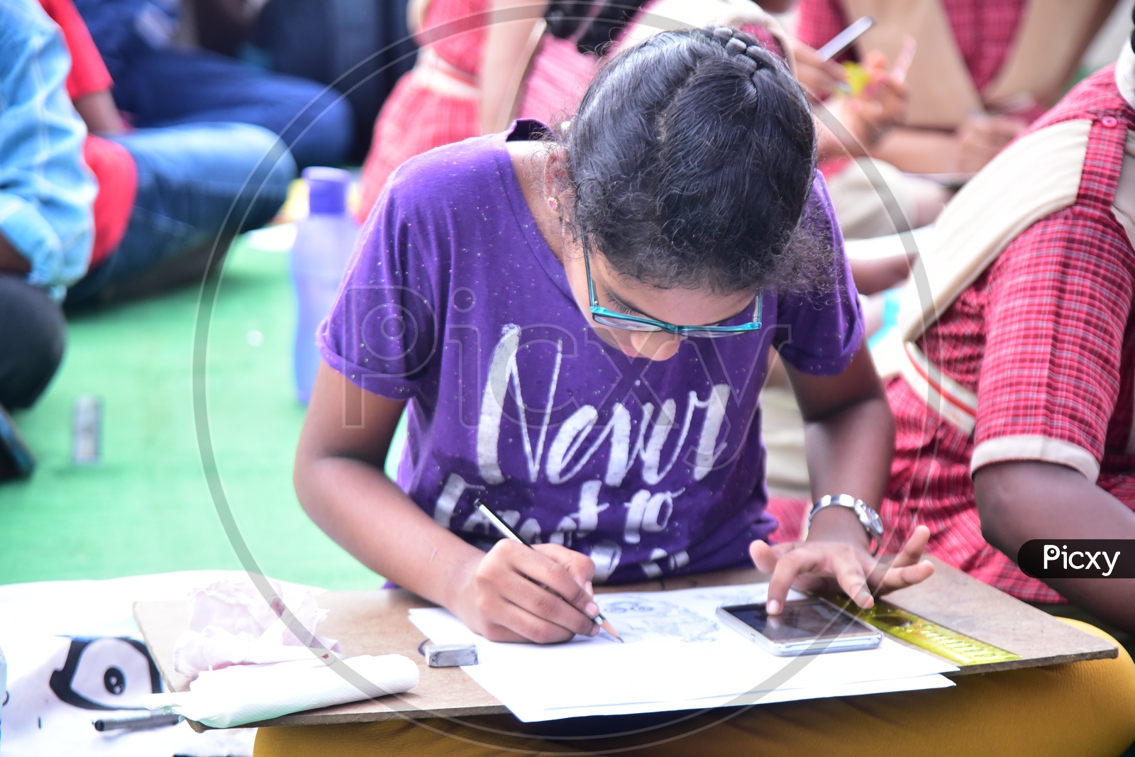 A school girl drawing a sketch using a cell phone during a competition