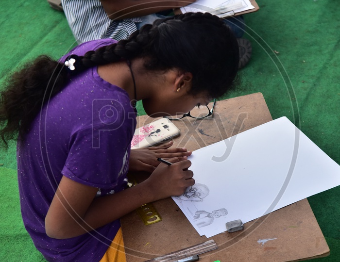 A school girl drawing a sketch of Mahatma Gandhi during a competition