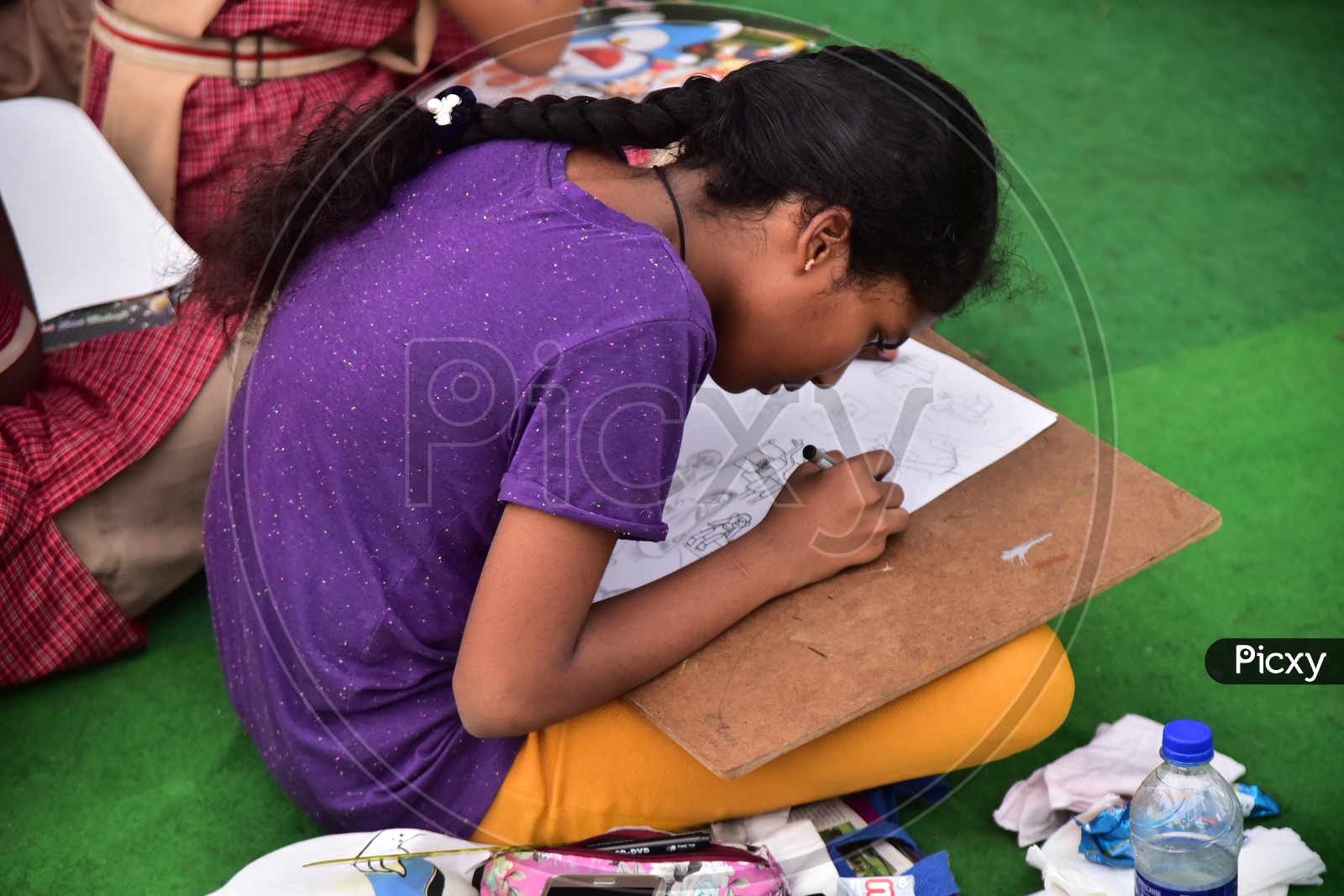 A school girl drawing a sketch during a competition