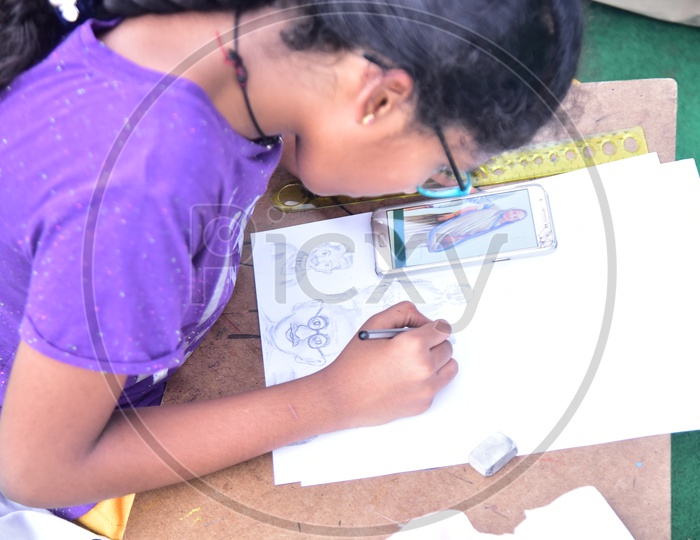 A school girl drawing a sketch using a cellphone during competition