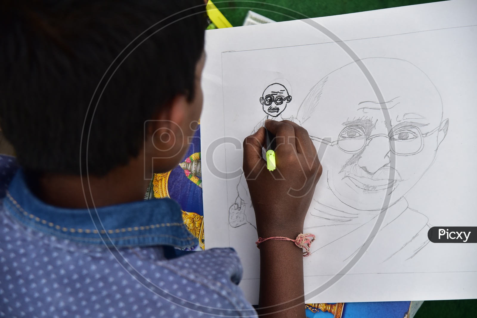 A school boy drawing a sketch of Mahatma Gandhi during a competition