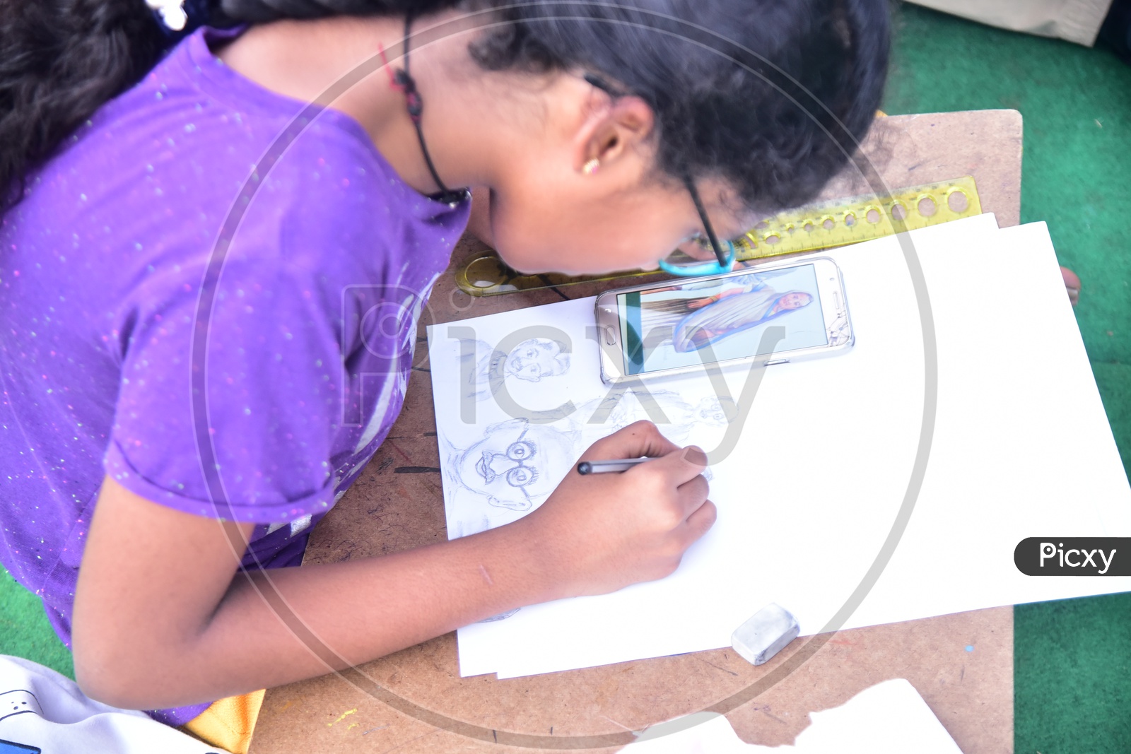A school girl drawing a sketch using a cellphone during competition