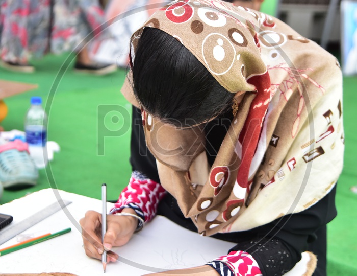 A muslim girl drawing a sketch during a competition
