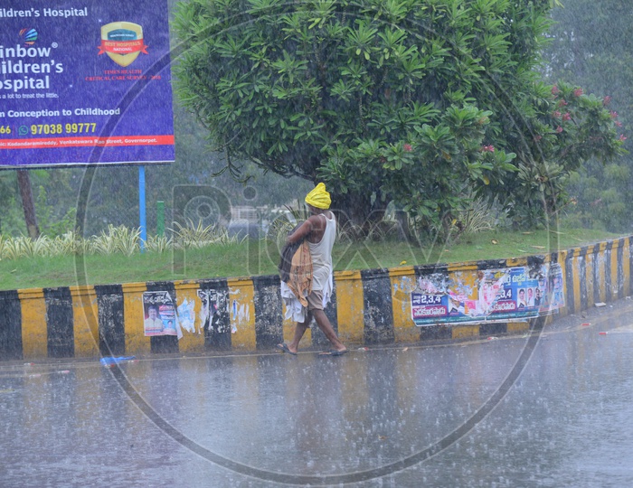 A man walking on the road while its raining