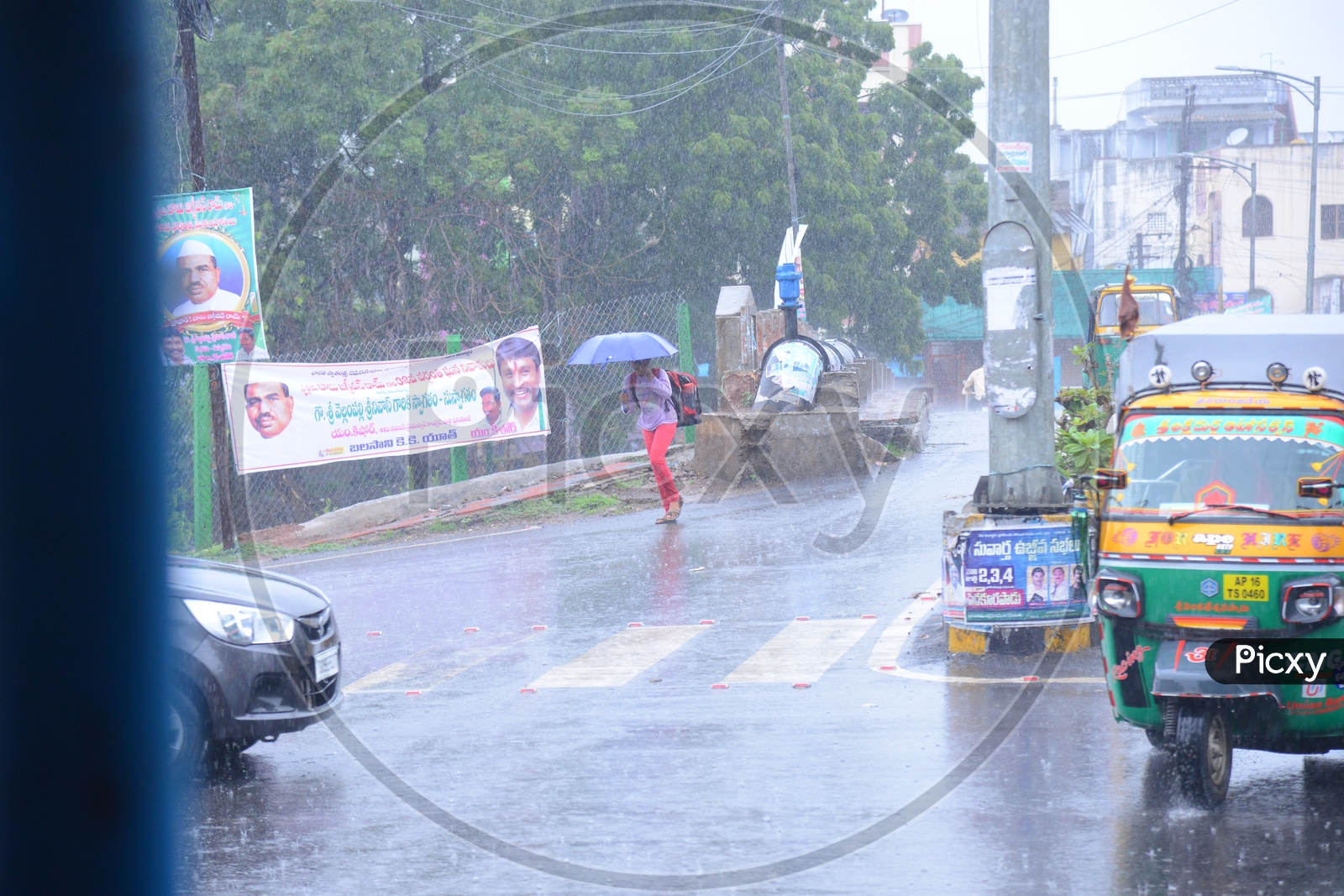 A girl walking with an umbrella on the road while its raining