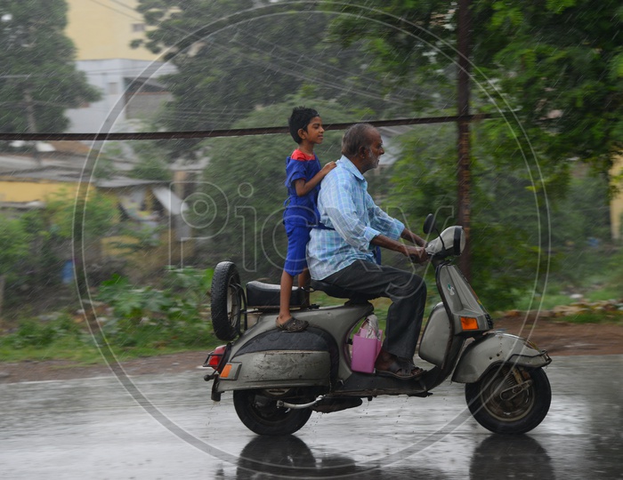 An old man driving scooter on road during rain