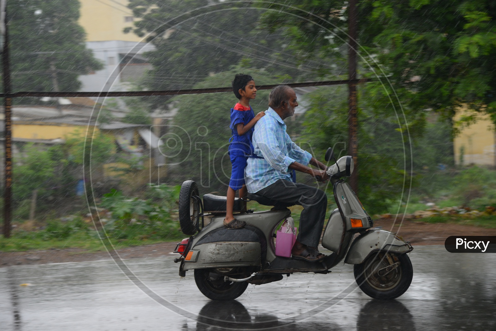 An old man driving scooter on road during rain