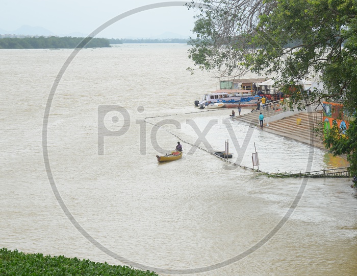 A man in a boat in Krishna river near a ghat