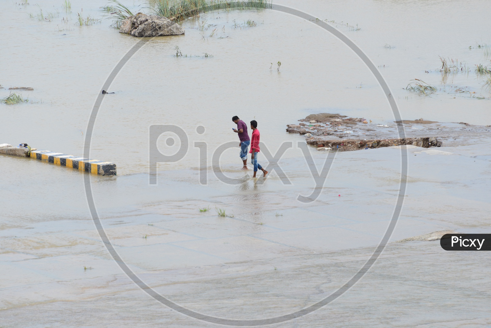 Men clicking pictures with mobile in Krishna River