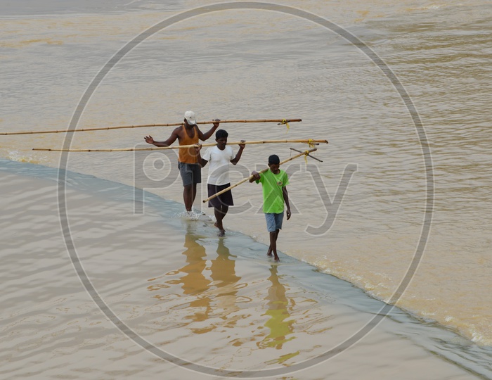 Men with wooden horseshoe weed rods in the river Krishna