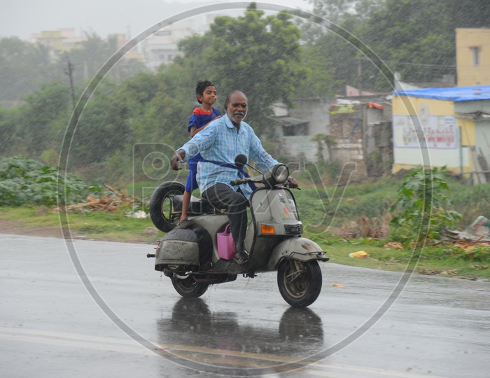 An old man driving a scooter on road during rain