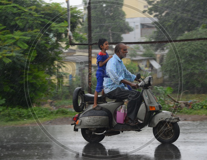 A man riding a scooter on road during rain