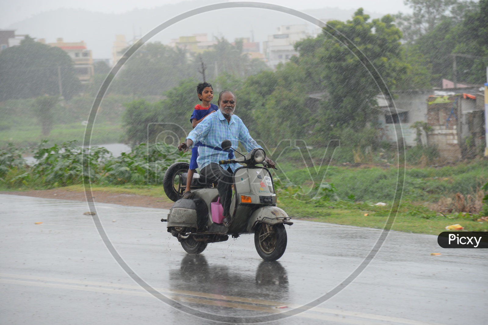 An old man driving a scooter on a road during rain