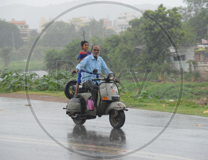 An old man driving a scooter on a road during rain