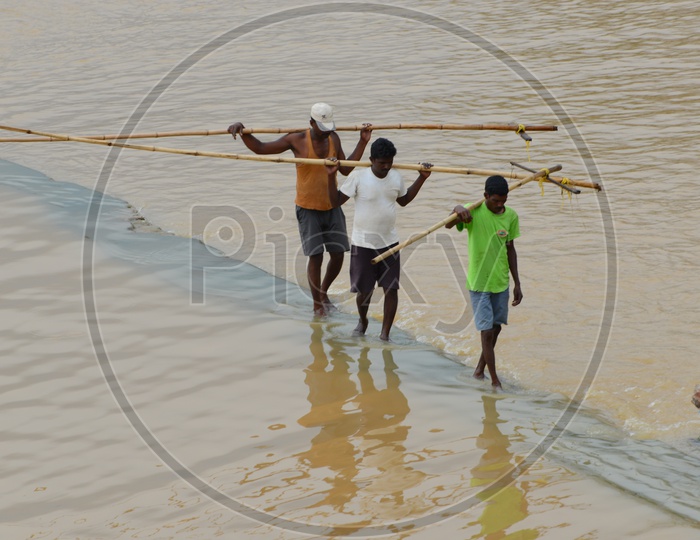 Men carrying wooden rods in Krishna river