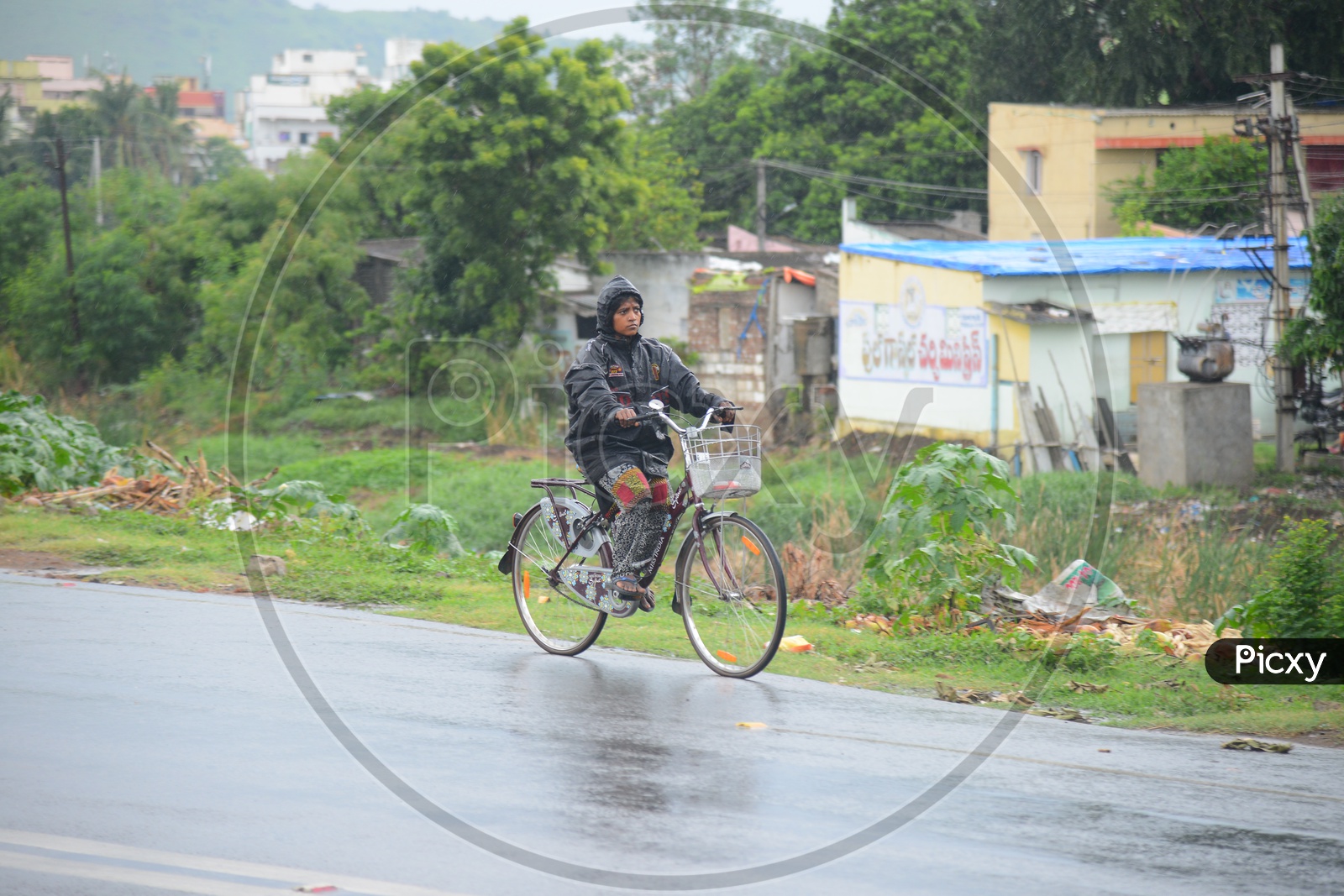 An Indian woman wearing raincoat and riding a bicycle