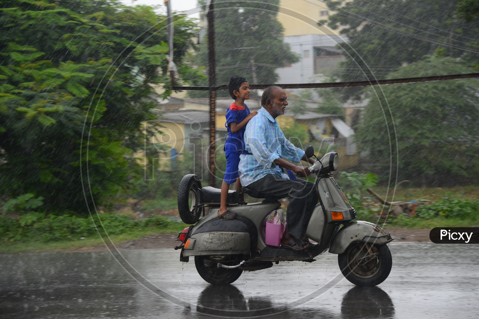 A man riding a scooter on road during rain