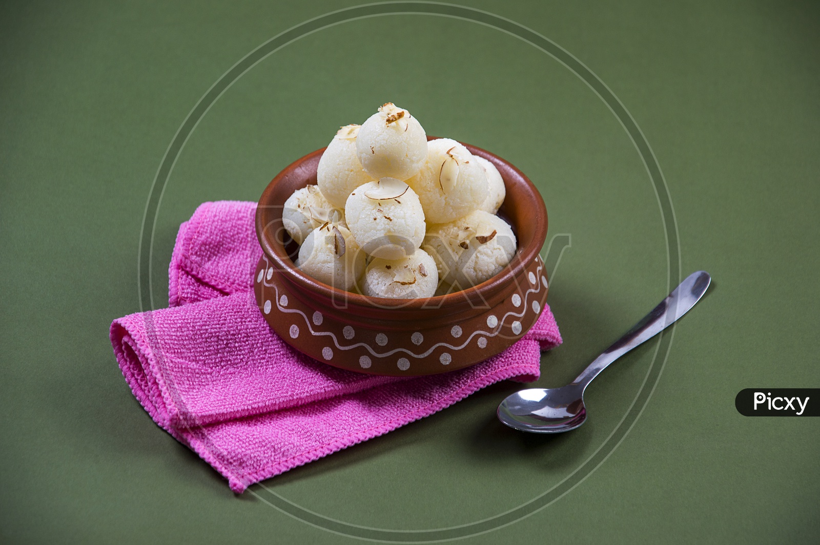 Rasgulla in a clay bowl with napkin and spoon