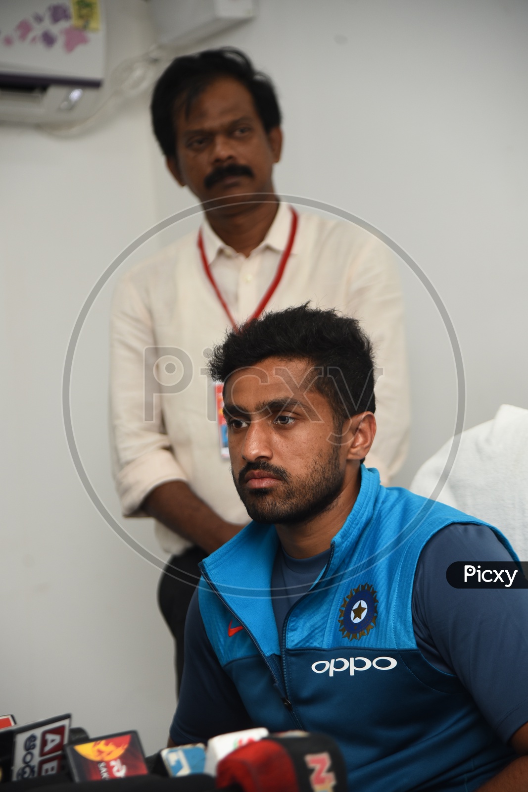 Cricketer Karun Nair speaking to the media - Telugu channels mikes placed on the table