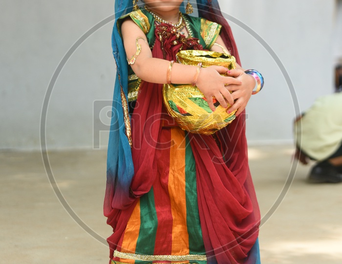 A little girl dressed as Gopika with a decorated earthen pot