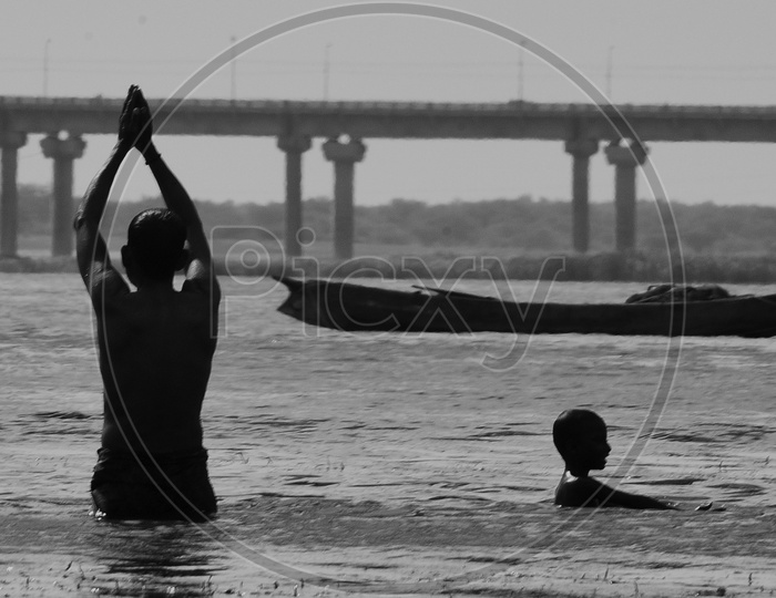A man doing Salutations to the Sun in Krishna river