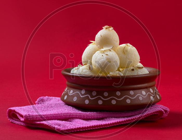 Rasgulla in a clay bowl with napkin on red background