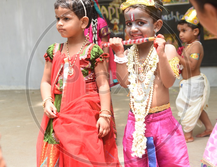 A little girl dressed as Gopika and A little boy dressed as Lord Krishna with a peacock feather on his head and a flute in his hand
