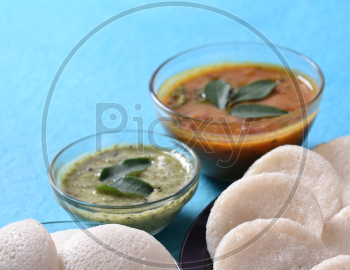 Idli with sambar and coconut chutney on blue background