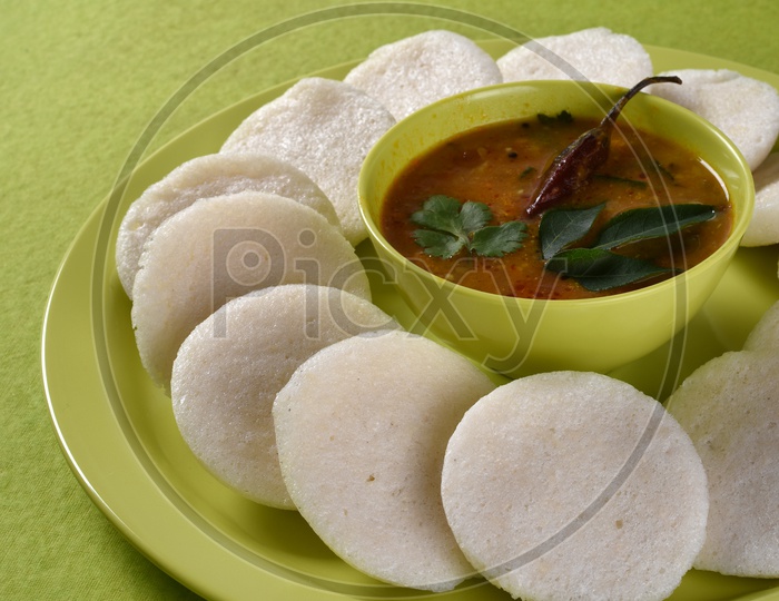Idli with Sambar in bowl on green background