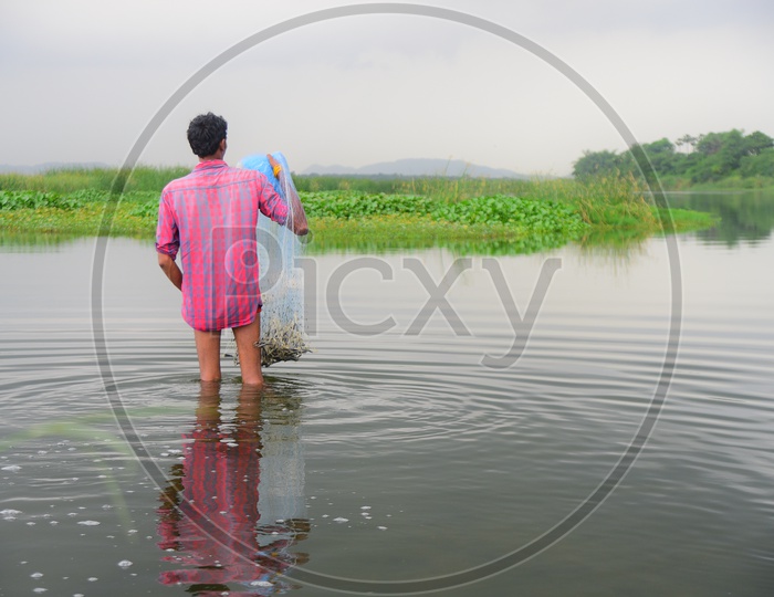 A man is casting a fish net into the water