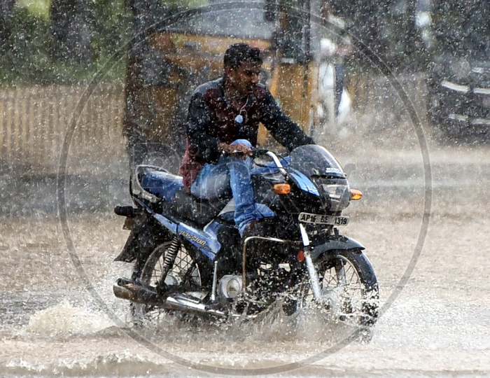 A man riding a bike on the road while it's raining