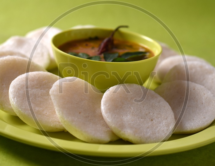 Idli with sambar on green background