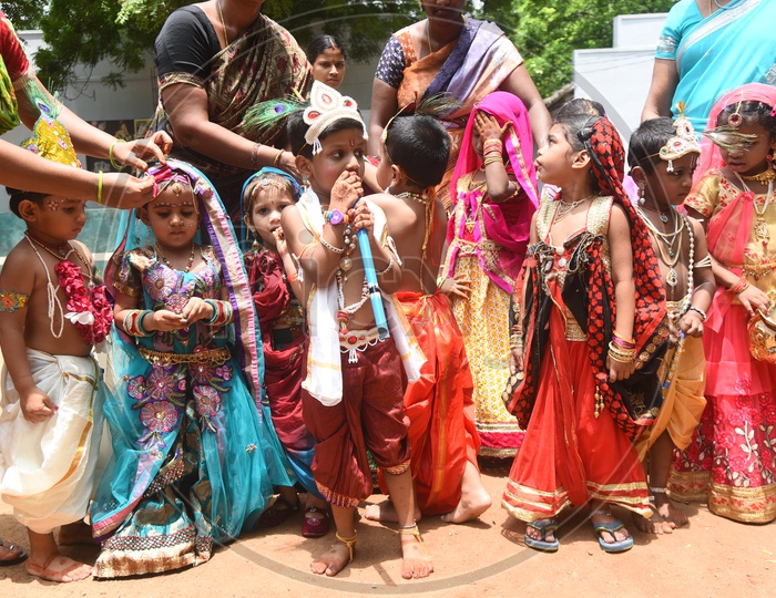 Little girls dressed as Gopika with pots in hand and Little boys dressed as Lord Krishna with a peacock feather on his head and a flute in his hand