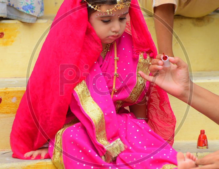 A little girl dressed as Gopika - Mom applying nail polish
