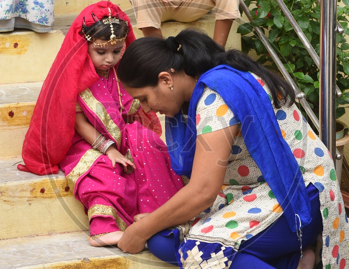 A little girl dressed as Gopika - Mom applying nail polish