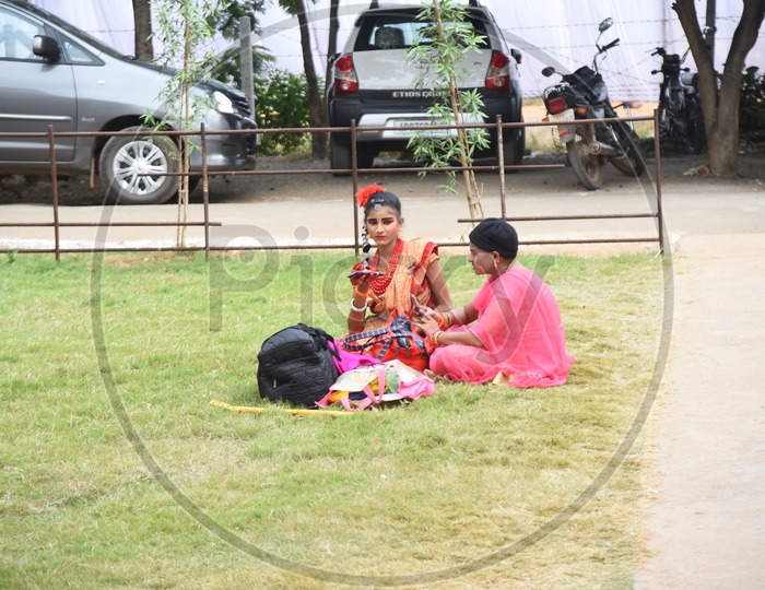 A costumed girl with her mother sitting on the lawn