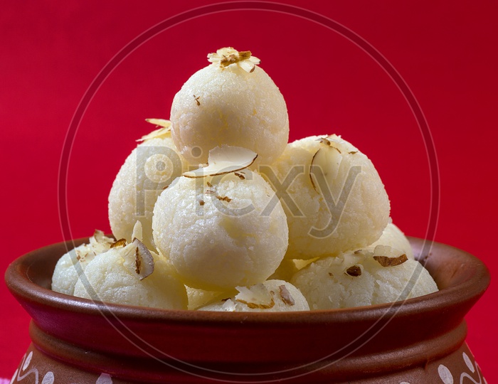 Rasgulla in a clay bowl on red background