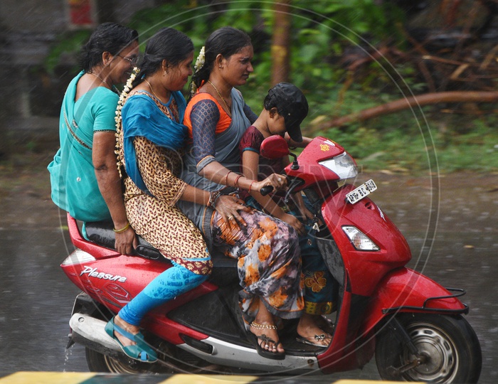 Four people on a Scooty on a rainy day